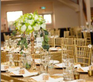 Elegant wedding tables set up at a country wedding venue near Calgary, featuring gold chairs and stunning floral centerpieces. The setup exudes a sophisticated and romantic ambiance, perfect for a memorable celebration