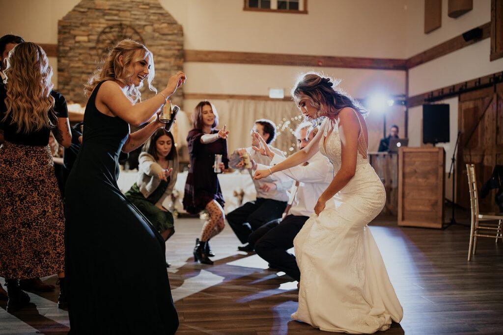 The bride dances joyfully with her friends, laughing and celebrating in a fun, lively moment at the reception.