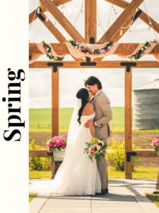 The bride and groom share a kiss under a rustic wooden arbour at a country wedding venue, surrounded by blooming spring flowers, capturing a romantic and picturesque moment