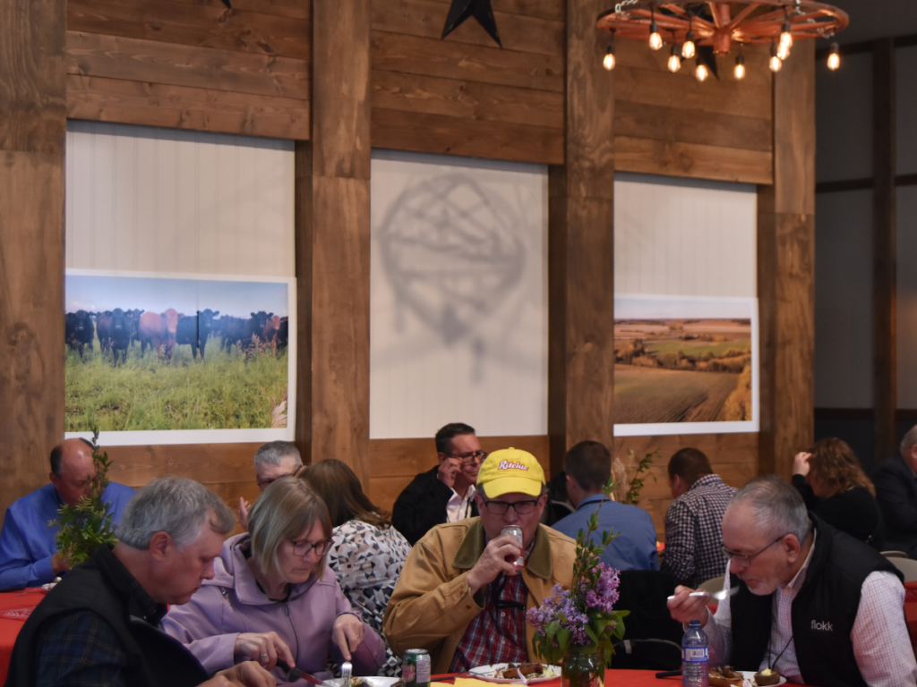 Conference attendees enjoying a catered lunch in a rustic, Western-style event centre adorned with artwork showcasing the agriculture industry.