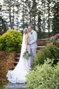 Bride and groom sharing a romantic kiss on an outdoor staircase at a beautiful country wedding venue, surrounded by scenic nature.