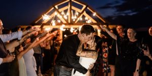 Bride and groom sharing a kiss surrounded by guests holding sparklers, creating a magical and celebratory atmosphere