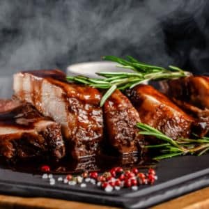 Juicy grilled steak garnished with herbs and served on a rustic wooden board — perfect for showcasing premium catering services.