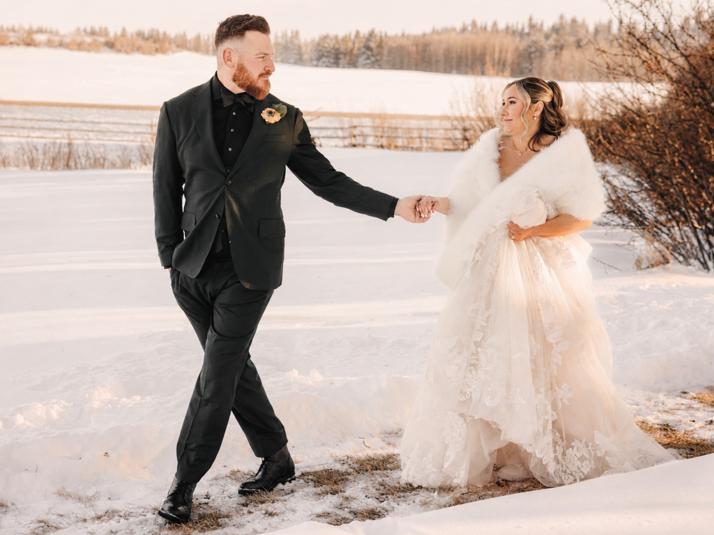 Avery leads Brittany by the hand through the snow during their winter wedding portraits in Alberta.