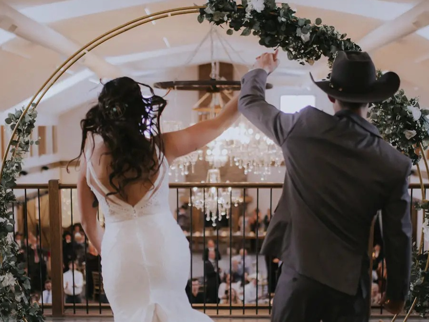 Bride and groom entering beneath a floral arch on the Grand Ballroom mezzanine.