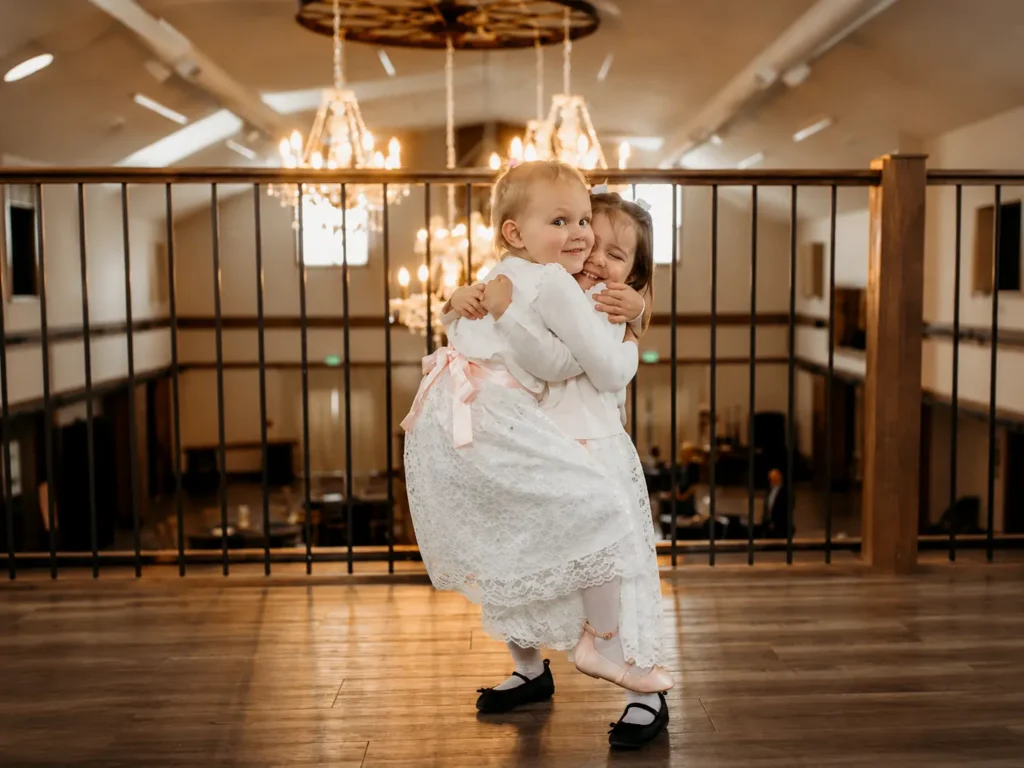 Two flower girls hugging on the mezzanine above the Grand Ballroom.