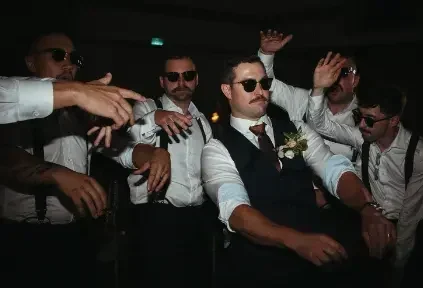 Groomsmen wearing sunglasses dancing together at a Heritage Centre wedding reception.