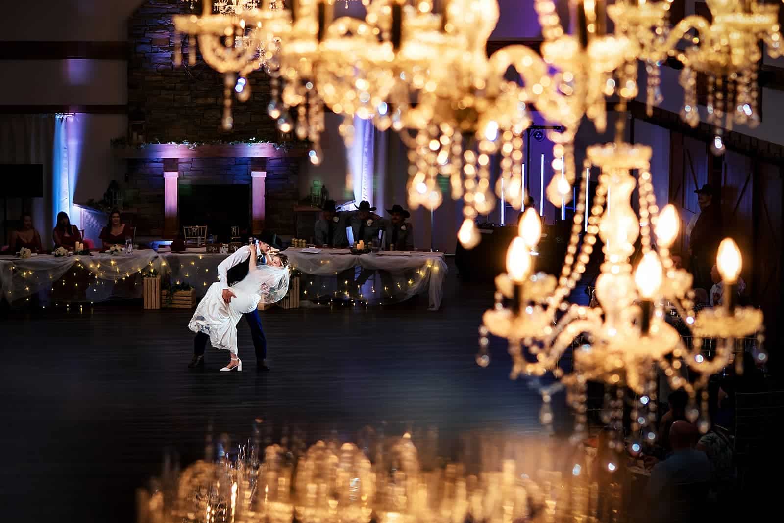Newlywed couple dancing beneath crystal chandeliers in the Grand Ballroom at The Heritage Centre in Cremona, Alberta.