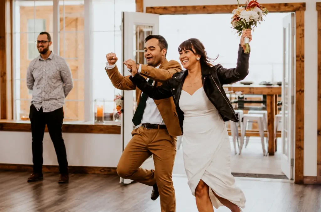 Newlywed couple making a joyful entrance into the Grand Ballroom at The Heritage Centre.