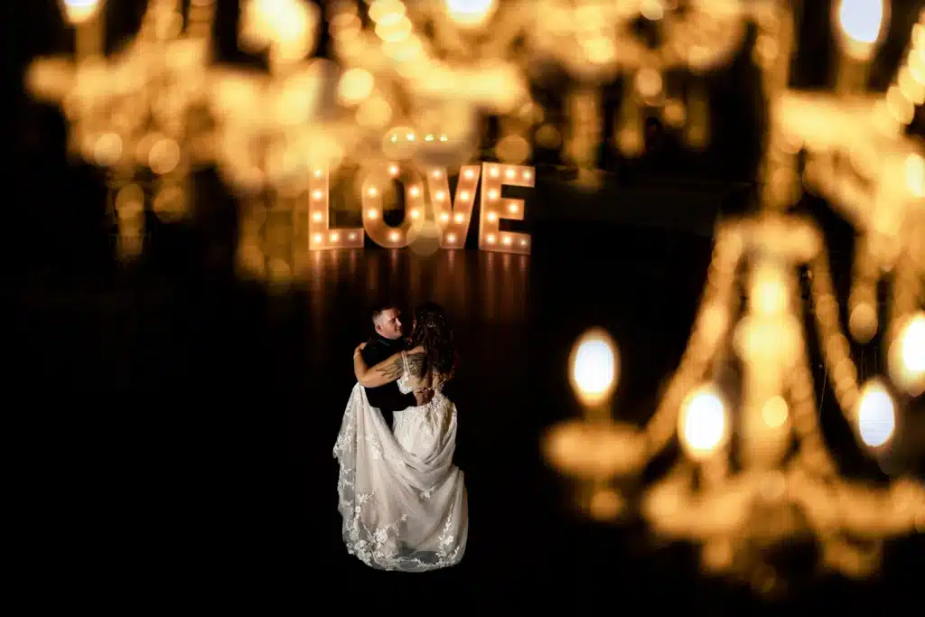 Newlywed couple dancing beneath an illuminated LOVE sign in the Grand Ballroom.