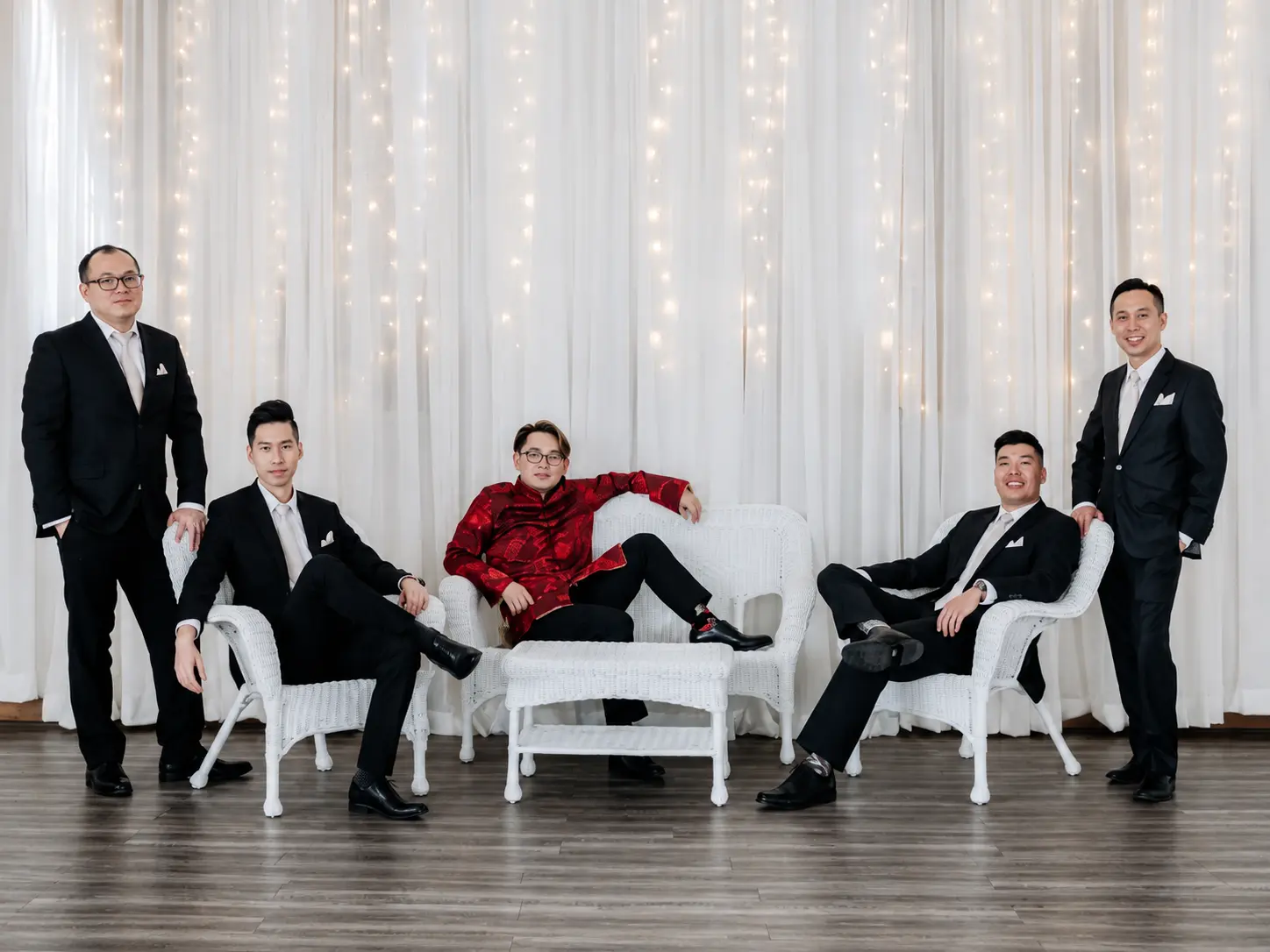 Wedding party posing on white furniture in front of the Grand Ballroom sparkle wall.