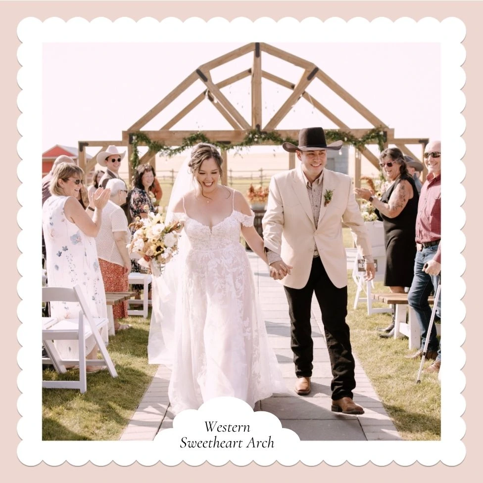 Nicole and Austin walking hand in hand beneath the Western Sweetheart Arch as guests cheer at The Heritage Centre, Central Alberta.