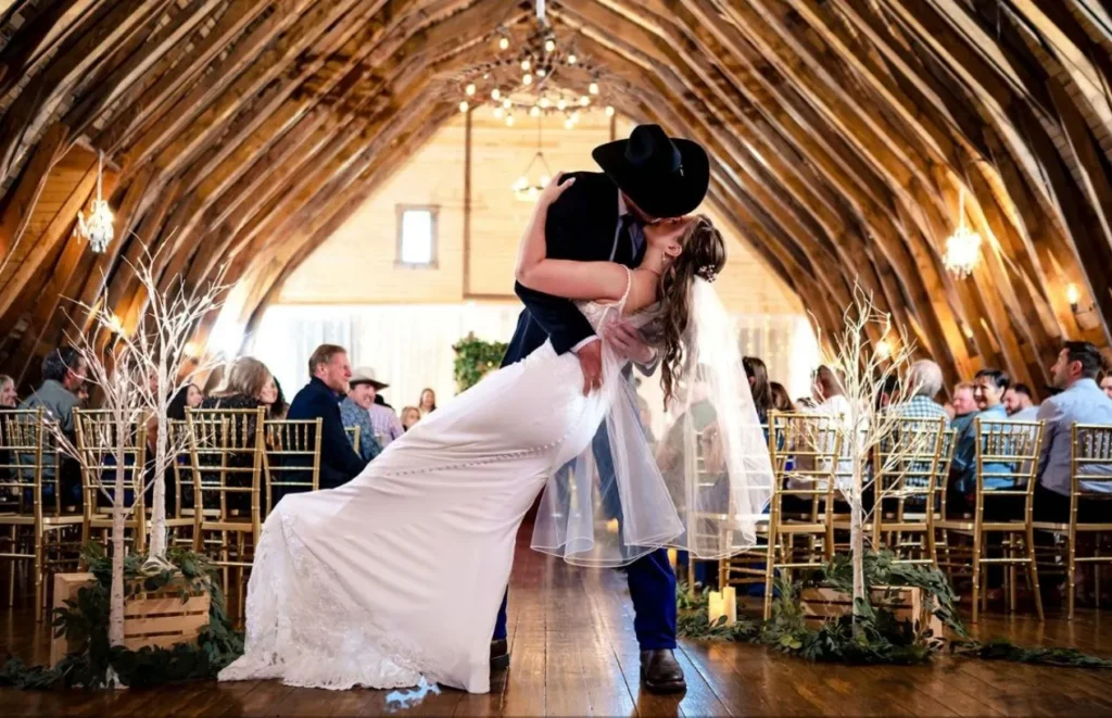 Bride and groom kissing during a wedding ceremony inside The Heritage Centre Historic Barn.