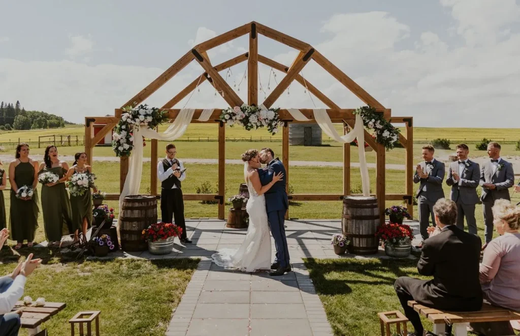 Bride and groom kissing beneath the Western Sweetheart Arch at The Heritage Centre.